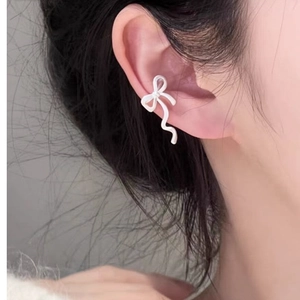 Detailansicht eines eleganten weißen Ohrclips in Schleifenform am Ohr eines Models