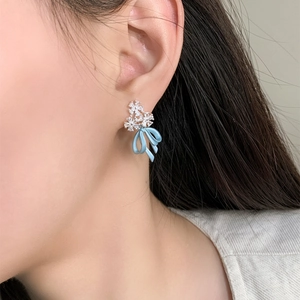Detail view of mist blue bow earrings with sparkling rhinestone flower cluster