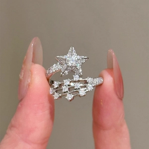 Nahaufnahme eines silbernen Sternrings mit funkelnden Zirkonia zwischen den Fingern