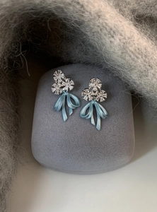 Macro detail view of elegant ice blue bow earrings featuring sparkling crystal floral studs