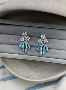 Detailed view of elegant light blue bow earrings with sparkling crystal floral accents