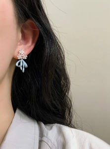 Close-up detail of ice blue bow drop earrings featuring sparkling floral cluster studs.