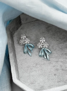 Detailed macro view of ice blue bow earrings with sparkling crystal flower accents