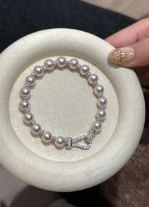 Close-up of elegant pink pearl bracelet with zircon encrusted U-shaped clasp.