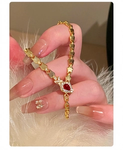 Macro view of a gold snake bone bracelet with a pigeon blood red teardrop gemstone