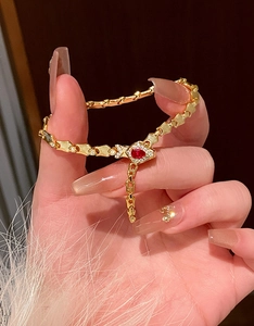 Elegant gold snake-bone bracelet with a pear-shaped ruby red gemstone accent
