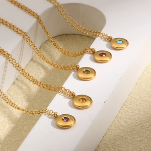 Detailed view of gold plated birthstone necklaces arranged on a white display stand