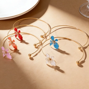 Close-up view of five colorful enamel flower collars with gold-tone metal bands