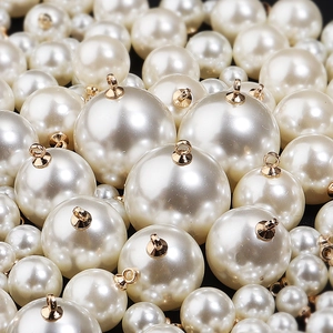 Macro detail of glossy white faux pearls with golden metal rings for DIY jewelry craft