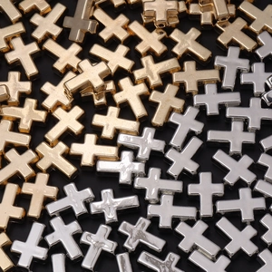Detalle de cuentas de metal en forma de cruz doradas y plateadas para joyería DIY