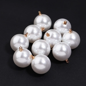 Set of ten high-gloss white round pearl charms with golden metal loops on black background