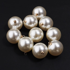 Close-up of ten cream white pearl charms with gold metal loops for DIY jewelry making