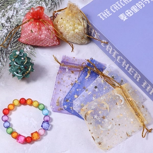 Organzabeutel mit Stern-Mond-Muster in Gold und bunte Perlenarmbänder als Geschenkverpackung