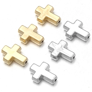 Detalle de cuentas de cruz pulidas en oro y plata con agujeros para creación de joyería