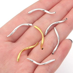 Close-up of gold and silver curved S-tube metal beads for DIY bracelet jewelry making