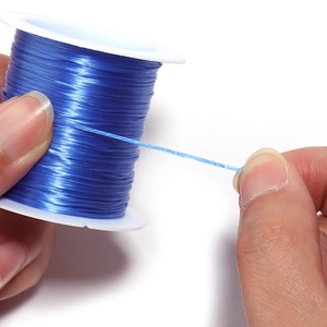 Close-up of flexible blue flat elastic bead cord on a spool for DIY jewelry making