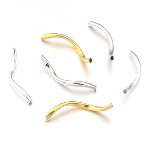 Macro detail of wave-shaped S-curve jewelry metal tube beads in gold and silver finish