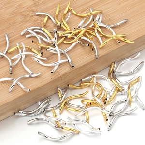 Detailed view of curved wave metal tubes in gold and silver for DIY jewelry making