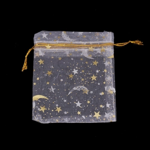 Nahaufnahme weißer Organza-Geschenkbeutel mit goldener Stern-Mond-Prägung und Kordel