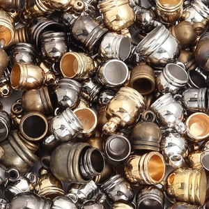 Macro shot of assorted metal tassel end caps in gold, silver, bronze, and gunmetal finishes