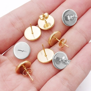 Macro shot of gold and silver flat pad ear studs with butterfly backs on a palm