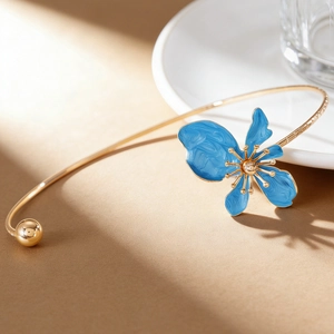 Close-up detail of a blue enameled floral petal on a vintage gold-tone neck cuff