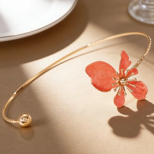 Detailed view of an elegant gold choker necklace featuring a coral enamel floral design