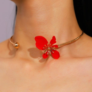 Macro detail of a vintage gold-tone torque necklace featuring a bold red enamel flower petal