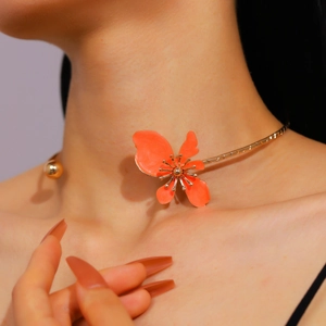 Close-up of a retro golden choker necklace featuring vibrant orange enamel flower petals