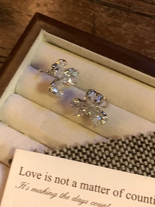 Close-up of sparkling heart-shaped flower ear clips in a luxury wooden box