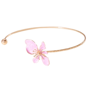 Close-up detail of an elegant gold-toned neck ring featuring a pink enamel flower charm