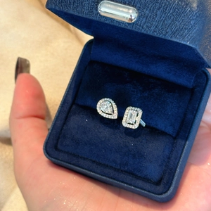 Detailed macro shot of an open zircon ring with pear and emerald stones in a navy box