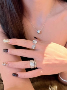 Macro detail of minimalist zircon open ring with teardrop and square stones on hand