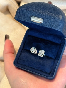 Detail view of a silver open ring with pear and emerald cut zircons in a blue jewelry box