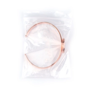 Detail van roségouden open armband met ronde bezel in plastic verpakking