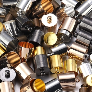 Macro view of assorted metallic cylindrical tassel caps with top loops for jewelry making