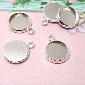 Detail view of five silver round bezel trays for DIY pendant making on floral background