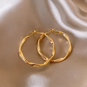 Exquisite Nahaufnahme goldener Wellen-Creolen mit schimmernden Mikropave-Kristalldetails