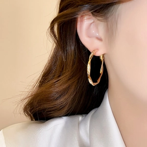 Nahaufnahme von eleganten goldenen gedrehten Creolen mit Mikropave auf einem Model