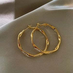 Detailansicht goldfarbene gewellte Creolen mit Mikro-Pavé-Zirkonia-Besatz