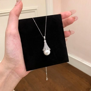 Detailed close-up view of elegant zircon bell-capped pearl pendant on black display card
