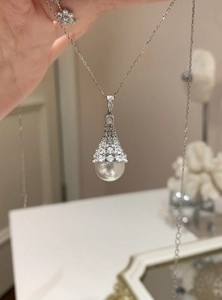 Detailed close-up of elegant zirconia pavé fan-shaped pendant with large round white pearl
