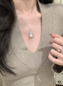 Detailed close-up of elegant zircon fan-shaped pearl pendant necklace on a model.