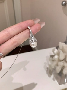 Detailed close-up of a silver zircon fan-shaped cap with a round white pearl pendant