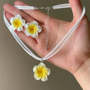 Macro view of Hawaiian style yellow and white Plumeria flower necklace and earring set