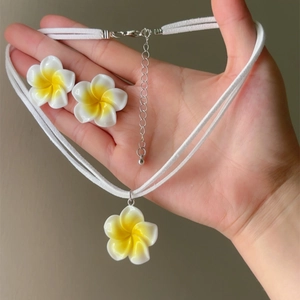 Detailed view of handmade white and yellow plumeria flower necklace and earring set