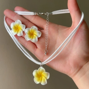 Detailed view of the white and yellow frangipani flower necklace and earrings jewelry set