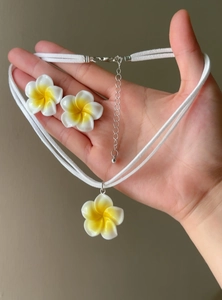 Close-up of hand holding a Hawaiian plumeria flower necklace and matching earrings set