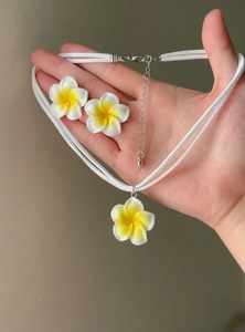 Detailed view of Hawaiian white and yellow plumeria flower necklace and earrings jewelry set