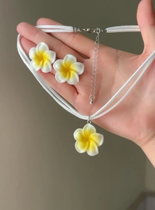 Handheld view of yellow white plumeria flower pendant necklace and earrings set